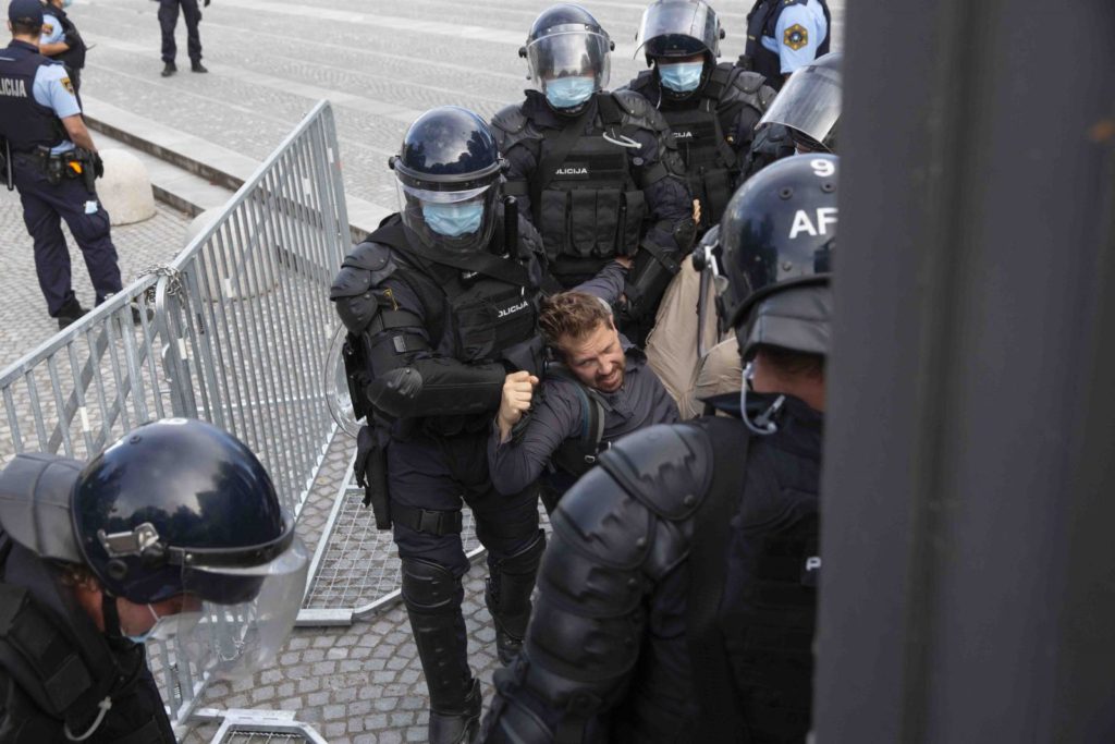 Policija odnaša Jenulla s protestnega branja ustave pred parlamentom. Policija je uporabila silo in odstranila protestnike, ki trga niso zapustili prostovoljno.